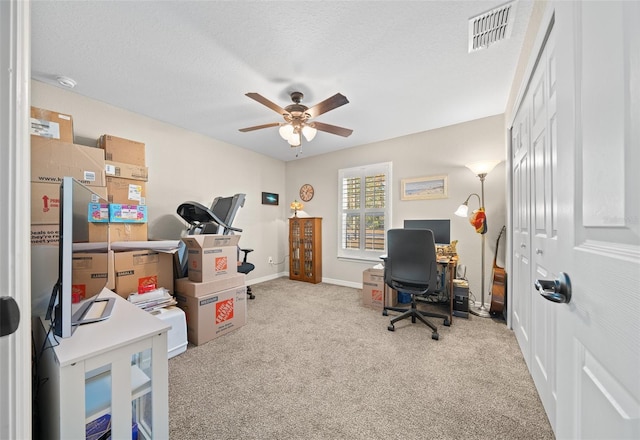 carpeted home office with a textured ceiling and ceiling fan