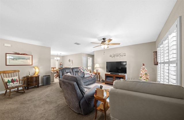 carpeted living room with ceiling fan with notable chandelier and plenty of natural light