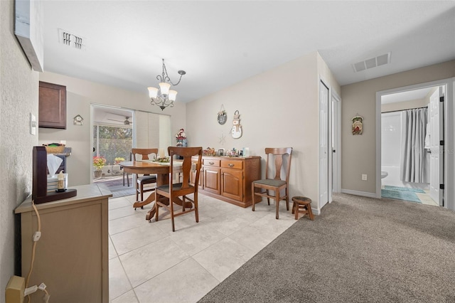 dining area with light carpet and a chandelier