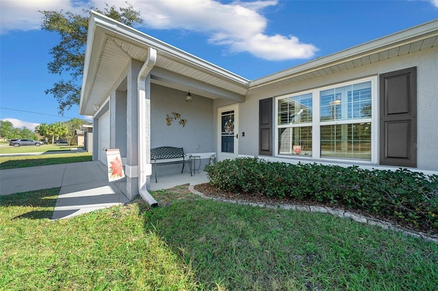 doorway to property with a garage and a lawn