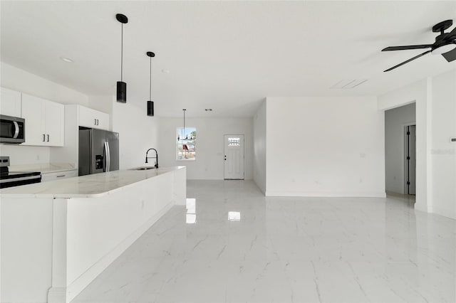 kitchen featuring a large island with sink, light stone countertops, appliances with stainless steel finishes, decorative light fixtures, and white cabinetry