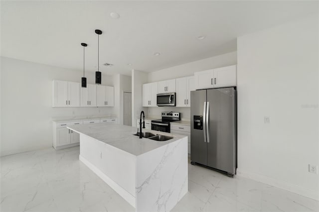 kitchen featuring light stone countertops, appliances with stainless steel finishes, a center island with sink, decorative light fixtures, and white cabinets