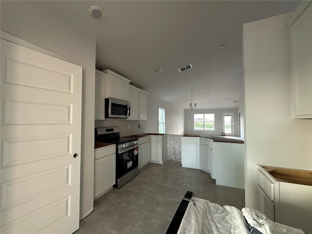 kitchen featuring kitchen peninsula, white cabinets, dark tile patterned flooring, and appliances with stainless steel finishes