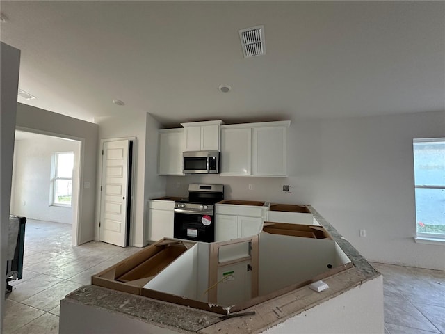 kitchen featuring white cabinets, light tile patterned floors, and appliances with stainless steel finishes