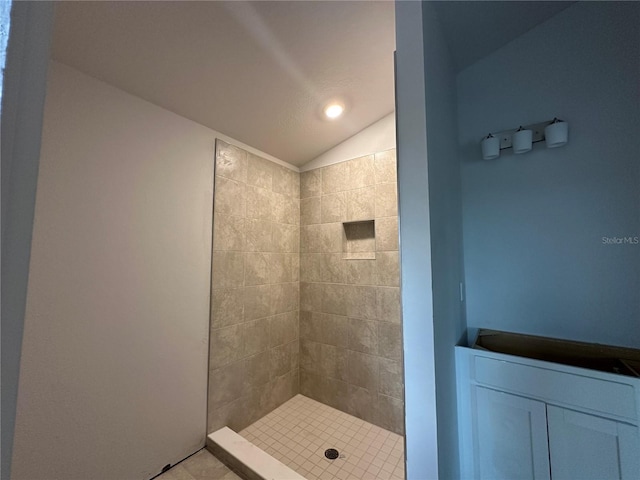 bathroom featuring a tile shower and lofted ceiling