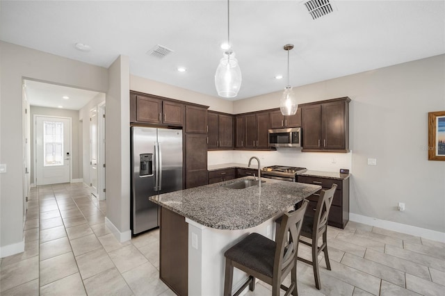 kitchen featuring pendant lighting, a center island with sink, sink, appliances with stainless steel finishes, and a breakfast bar area