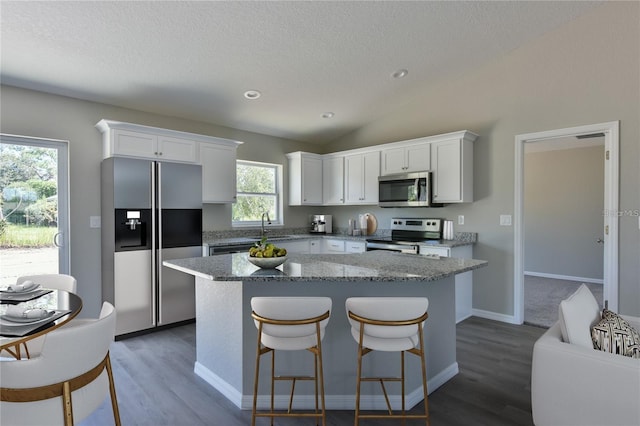 kitchen featuring a textured ceiling, stainless steel appliances, dark wood-type flooring, white cabinetry, and lofted ceiling