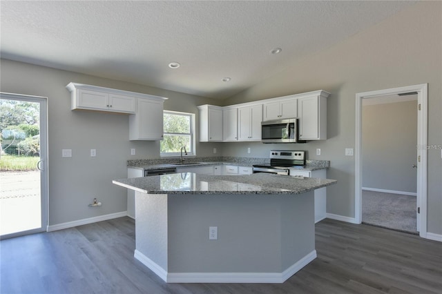 kitchen featuring white cabinets, a center island, stainless steel appliances, and vaulted ceiling