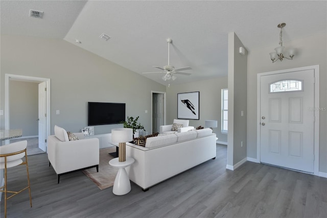 living room featuring ceiling fan with notable chandelier, lofted ceiling, and hardwood / wood-style flooring