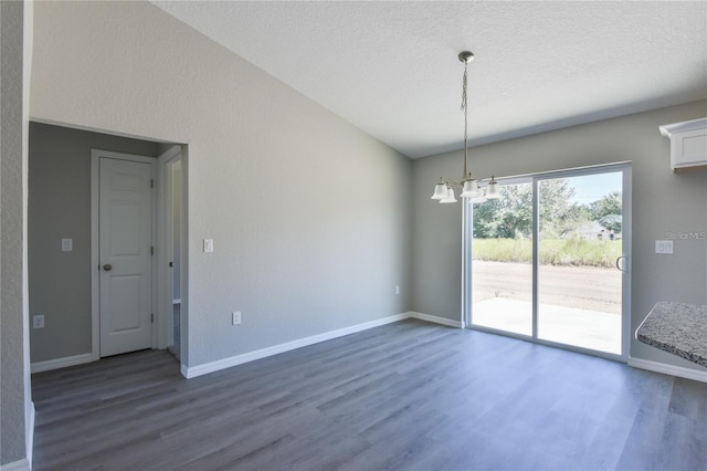 spare room with dark hardwood / wood-style flooring, a textured ceiling, and a chandelier