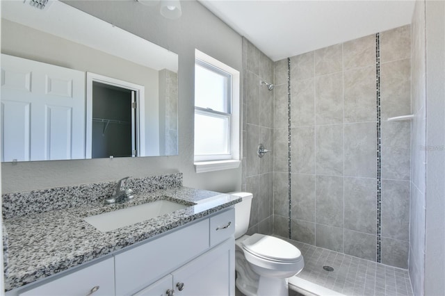 bathroom with vanity, toilet, and tiled shower