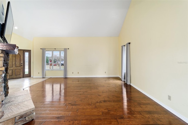 unfurnished living room featuring a stone fireplace, high vaulted ceiling, and hardwood / wood-style flooring