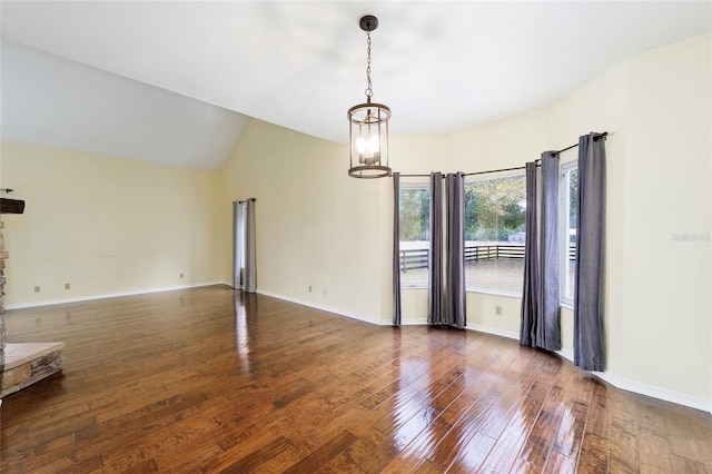 spare room with a notable chandelier, dark wood-type flooring, and vaulted ceiling