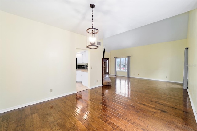 unfurnished living room with an inviting chandelier and hardwood / wood-style flooring