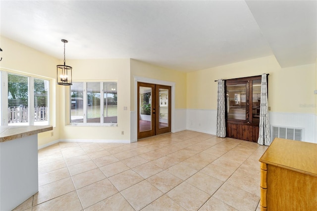 interior space featuring french doors, a notable chandelier, and light tile patterned flooring