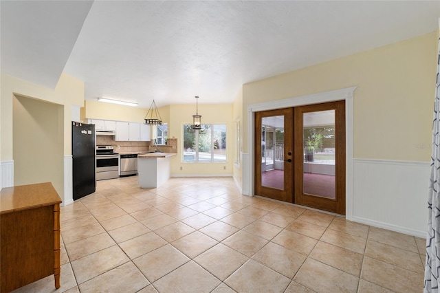 kitchen with french doors, stainless steel appliances, light tile patterned floors, white cabinets, and hanging light fixtures