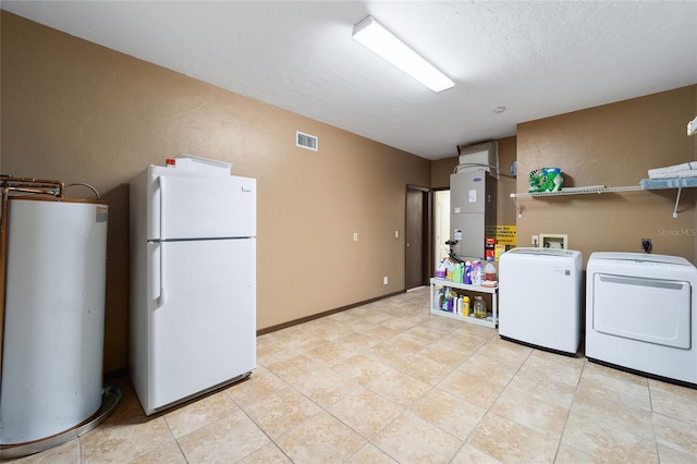 laundry area with washing machine and dryer, water heater, heating unit, a textured ceiling, and light tile patterned floors