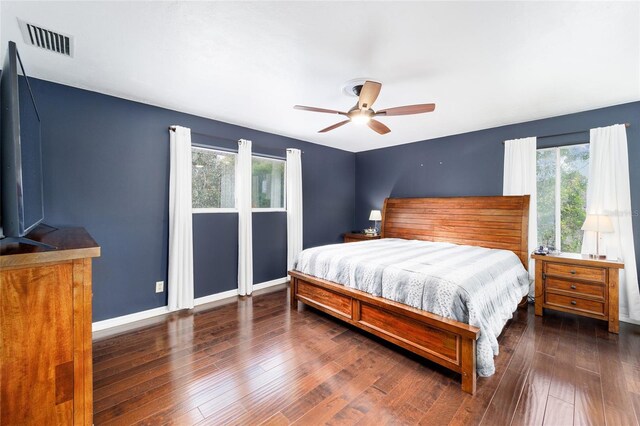 bedroom featuring multiple windows, dark hardwood / wood-style floors, and ceiling fan