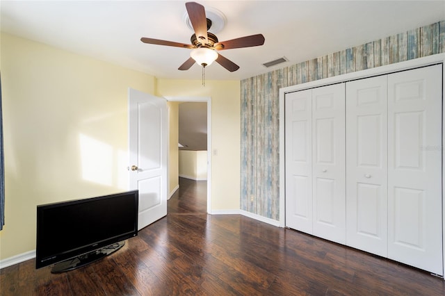 unfurnished bedroom featuring ceiling fan, a closet, and dark wood-type flooring