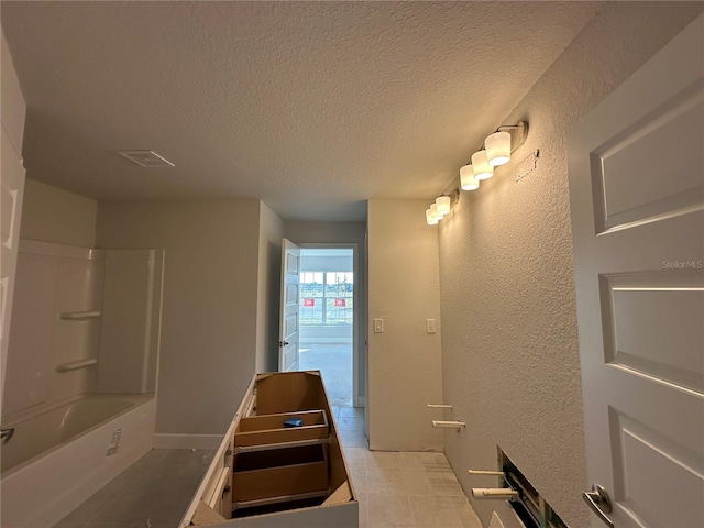 bathroom featuring tile patterned floors, tub / shower combination, and a textured ceiling