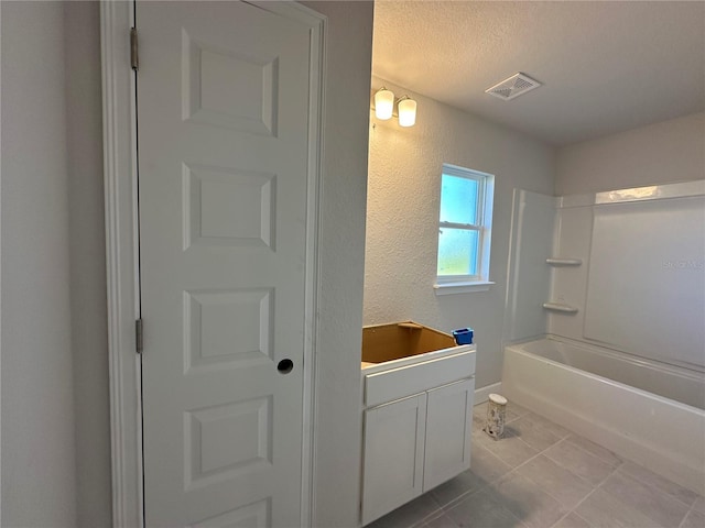 bathroom featuring tile patterned floors, a textured ceiling, vanity, and bathtub / shower combination