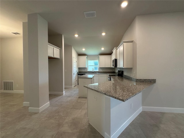 4445 SW 90th Pl, Ocala, FL 34476 - kitchen with stainless steel electric range, a peninsula, a sink, black microwave, and dark stone countertops