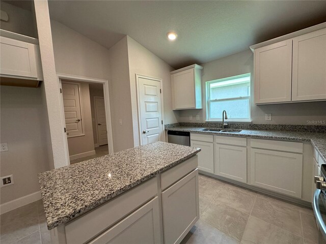 4445 SW 90th Pl, Ocala, FL 34476 - kitchen with a sink, dishwasher, vaulted ceiling, light stone countertops, and white cabinets