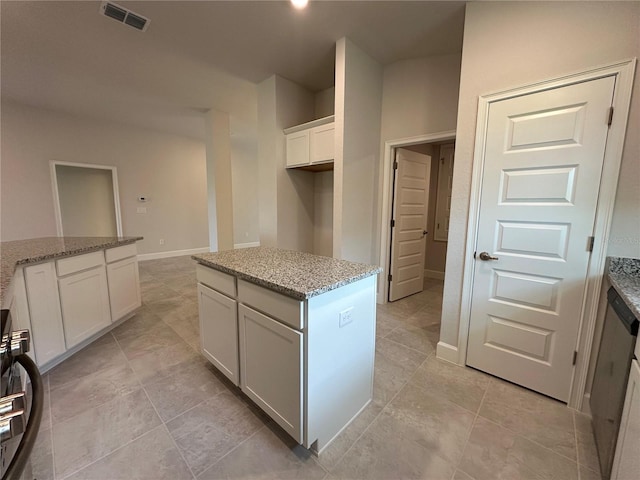 4445 SW 90th Pl, Ocala, FL 34476 - kitchen featuring white cabinets, light stone countertops, baseboards, a center island, and light tile patterned floors