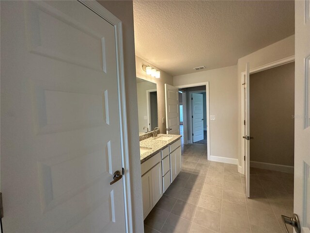 4445 SW 90th Pl, Ocala, FL 34476 - bathroom featuring double vanity, baseboards, a textured ceiling, and tile patterned flooring