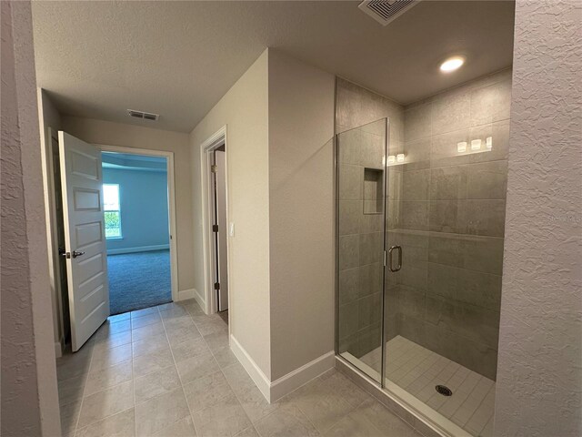 4445 SW 90th Pl, Ocala, FL 34476 - bathroom featuring a textured wall, a textured ceiling, a shower stall, baseboards, and tile patterned flooring