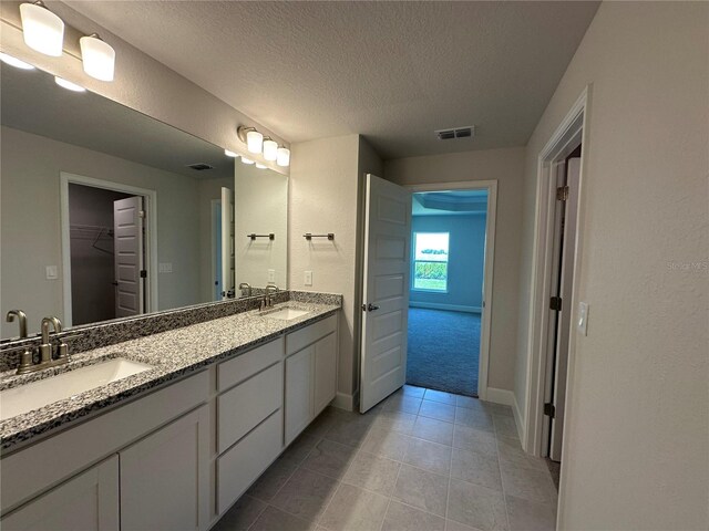 4445 SW 90th Pl, Ocala, FL 34476 - full bath with a textured ceiling, tile patterned flooring, double vanity, a walk in closet, and baseboards