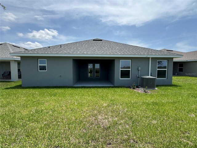 4445 SW 90th Pl, Ocala, FL 34476 - back of house with central AC, a shingled roof, a patio area, stucco siding, and a yard
