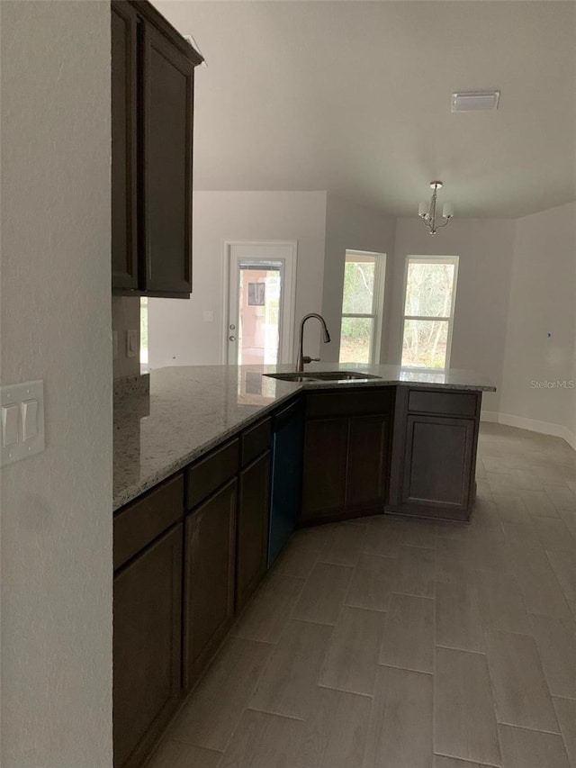 kitchen featuring dark brown cabinetry, sink, light stone counters, black dishwasher, and kitchen peninsula