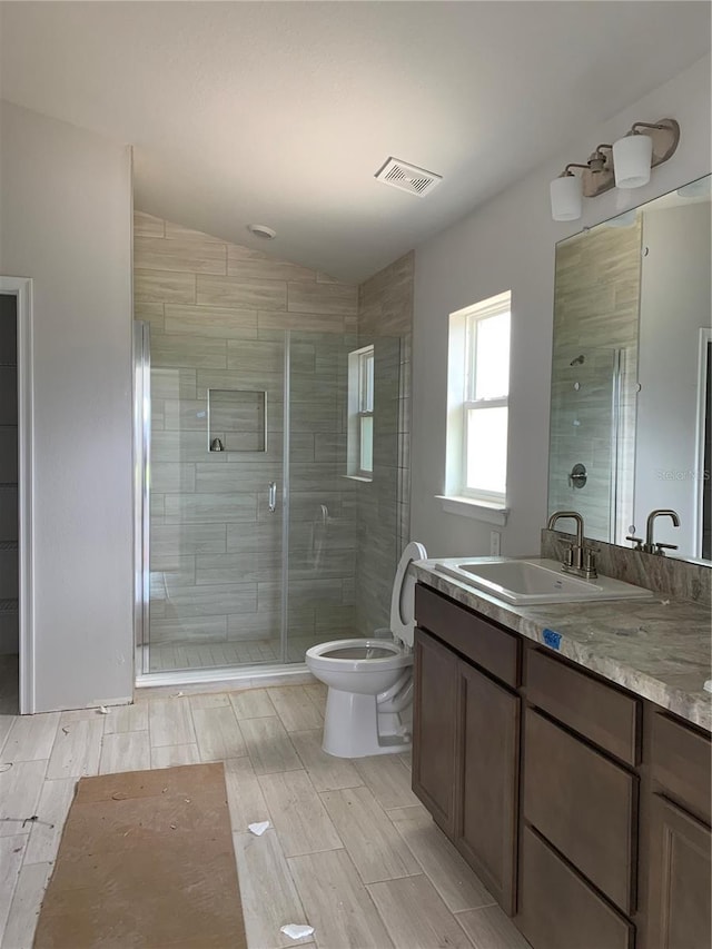 bathroom featuring vanity, a shower with shower door, lofted ceiling, and toilet