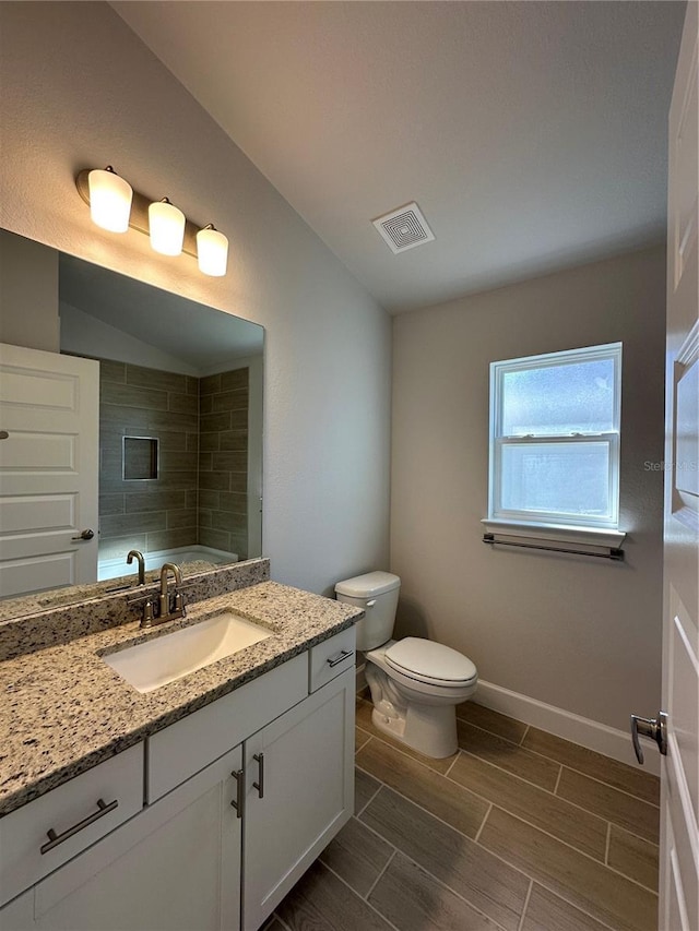 bathroom featuring vanity, vaulted ceiling, and toilet