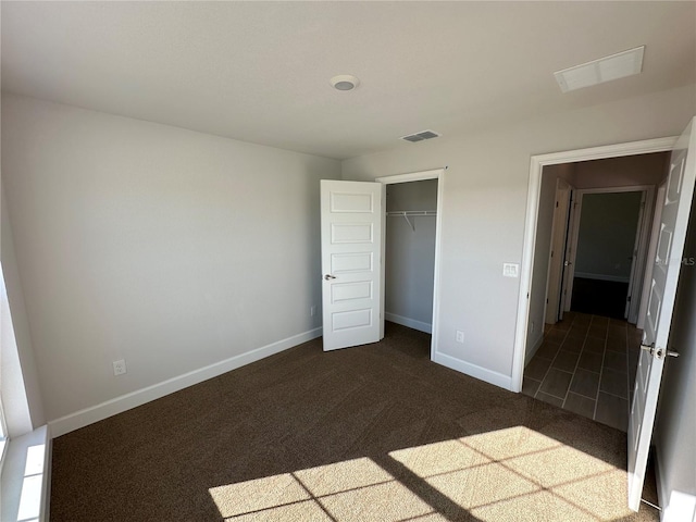 unfurnished bedroom with dark colored carpet and a closet