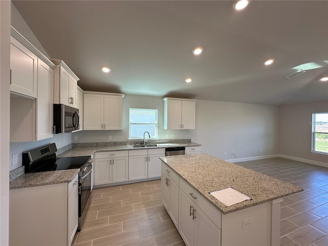 kitchen featuring light stone countertops, stainless steel appliances, light hardwood / wood-style flooring, white cabinets, and a kitchen island