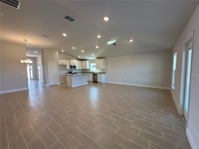 unfurnished living room with vaulted ceiling, a notable chandelier, and light wood-type flooring