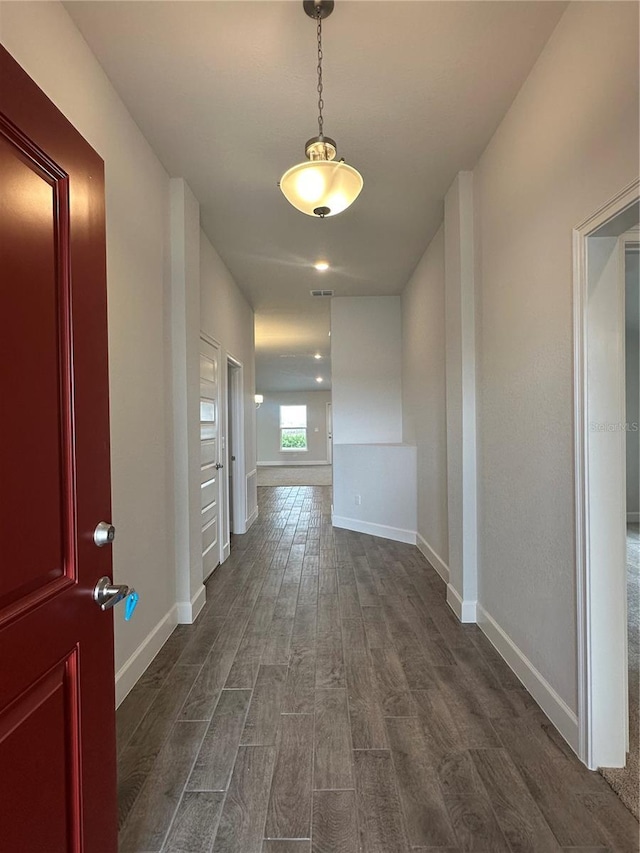 corridor featuring baseboards and dark wood finished floors