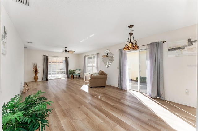 unfurnished room with a textured ceiling, ceiling fan with notable chandelier, and light hardwood / wood-style floors