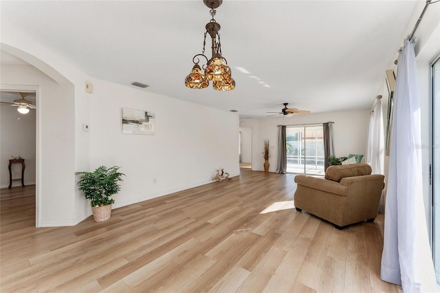 living room with ceiling fan with notable chandelier and light wood-type flooring