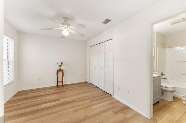 bedroom featuring ensuite bathroom, ceiling fan, light hardwood / wood-style floors, and a closet