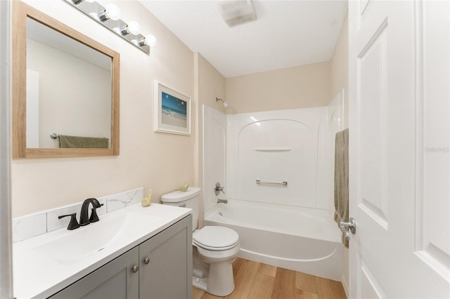 full bathroom with vanity, bathtub / shower combination, hardwood / wood-style flooring, toilet, and a textured ceiling