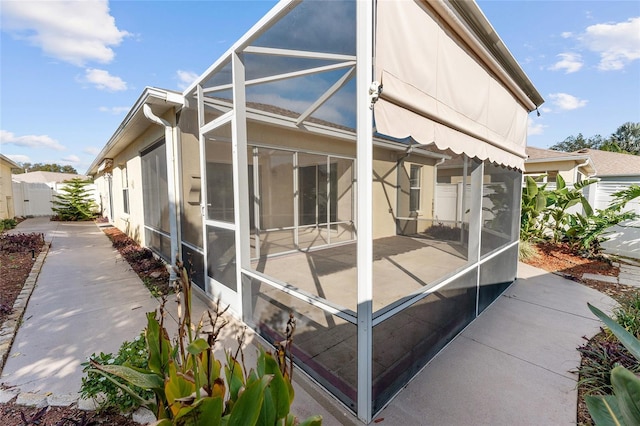 view of side of home featuring glass enclosure