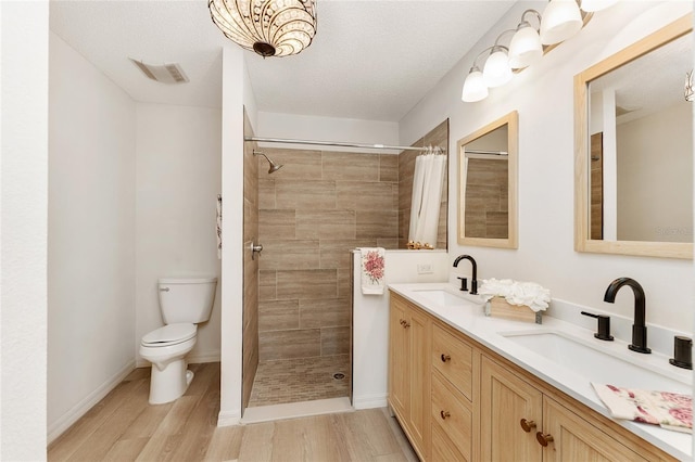 bathroom with hardwood / wood-style floors, a shower with shower curtain, a textured ceiling, and toilet