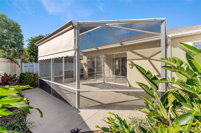 back of property with glass enclosure and a patio area