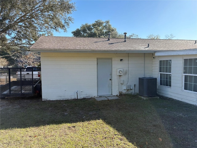 rear view of property featuring central air condition unit and a yard