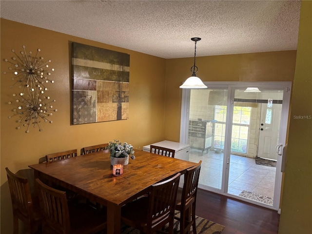 dining space featuring dark wood-type flooring and a textured ceiling