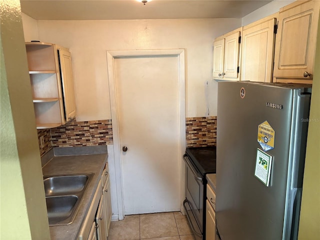 kitchen with sink, backsplash, stainless steel refrigerator, black electric range oven, and light tile patterned flooring