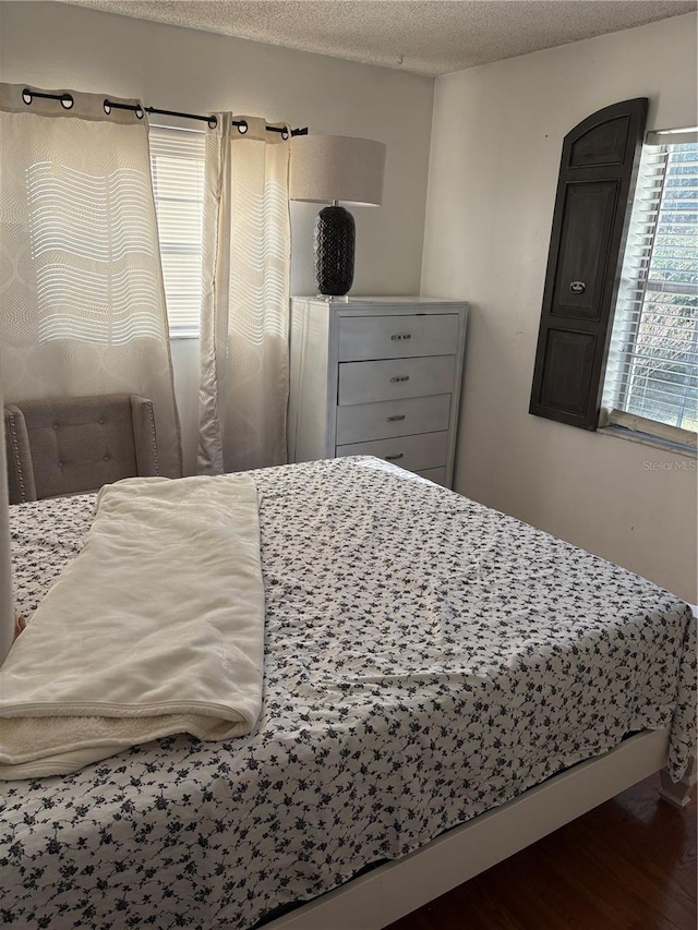 bedroom with dark hardwood / wood-style floors and a textured ceiling